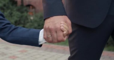 Okula yürürken çocuğun ve babanın el ele tutuşmalarını yakından izleyin. Aile, çocuk ve eğitim kavramı.