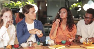 Bir grup neşeli insan kafede kruvasan yerken birlikte vakit geçiriyorlar. Samimi bir restoranda yemek masasında oturup yemek yerken gülümseyen meslektaşlar. Dışarıda yemek kavramı..