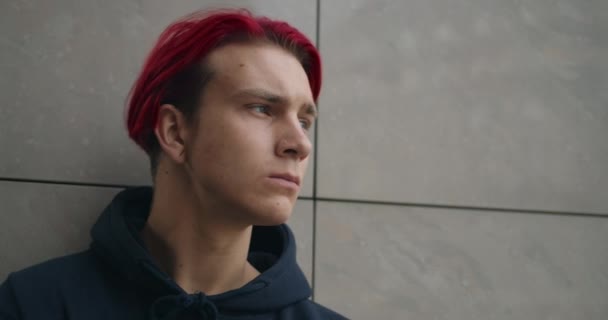 Retrato de jovem hipster masculino sério olhando para o lado. Vista de perto do homem milenar com cabelo tingido de vermelho em pé na rua. Conceito de juventude e estilo de vida. — Vídeo de Stock