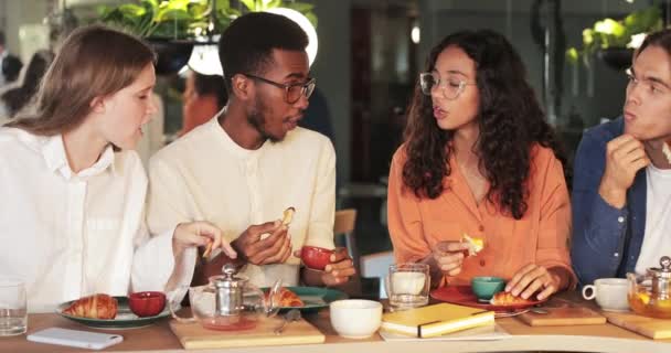 Filles amies joyeux parler et sourire tout en traînant dans un café moderne. Groupe d'étudiants multiethniques mangeant et communiquant pendant le déjeuner. Concept de manger dehors et de loisirs. — Video