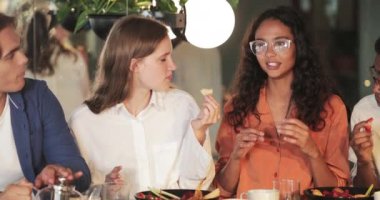 Modern kafede yemek yiyen ve sohbet eden arkadaşlar. Neşeli milenyum erkekleri ve kızları eğlenirken konuşup gülüyorlar. Olumlu duygular kavramı.