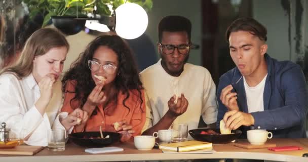 Bir grup genç arkadaş birlikte vakit geçirirken kafede lezzetli yemekler yiyorlar. Konforlu restoran masasında oturup yemek yerken, yemek yerken mutlu iş arkadaşları. Dışarıda yemek kavramı.. — Stok video