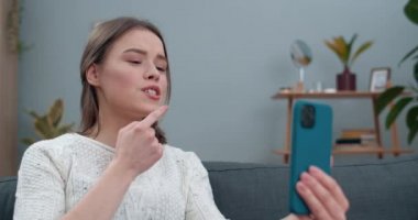 Sağır dilsiz işaret diliyle konuşan çekici bir kadının kanepede otururken seni nasıl özlediğini yakından izlerim. Video ararken akıllı telefon kullanan genç bir kadın..