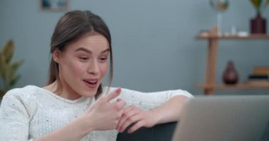 Kadın video konuşma yapıyor ve laptop kamerası kullanıyor. Güzel bayan gülümseyip işaret diliyle soruyor. Merhaba, kanepede otururken nasılsın? İşitme kaybı kavramı.