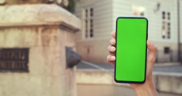 Vista de cerca de las manos femeninas con diseño de uñas de moda que sostiene el teléfono inteligente con pantalla verde. Fuente de la ciudad vieja en el fondo. Concepto de maqueta y clave de croma. — Vídeos de Stock