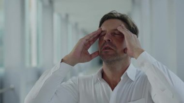 Stresli iş adamlarının portresi tapınaklar ve dua jestlerinde el ele tutuşuyor. Yorgun bir girişimci iş yerinde yorgunluk ve baskıdan muzdarip.