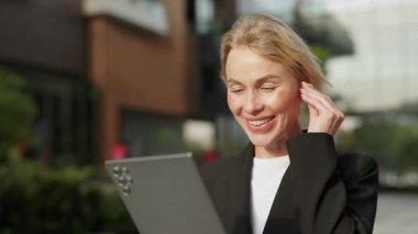 Dost canlısı kadın danışman portresi Sunny Caddesi 'ndeki dijital tablet aracılığıyla merhaba diyor. Girişimci kadın, şehir merkezinde mobil cihazın kulaklığını takarak gülüyor