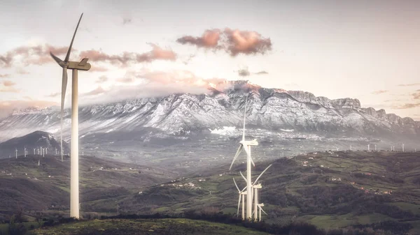 Global warming, climate change. Turbines on the field on the sunset sky. Alternative energy source. Wind farm in Italy. Eco power, green technology concept.