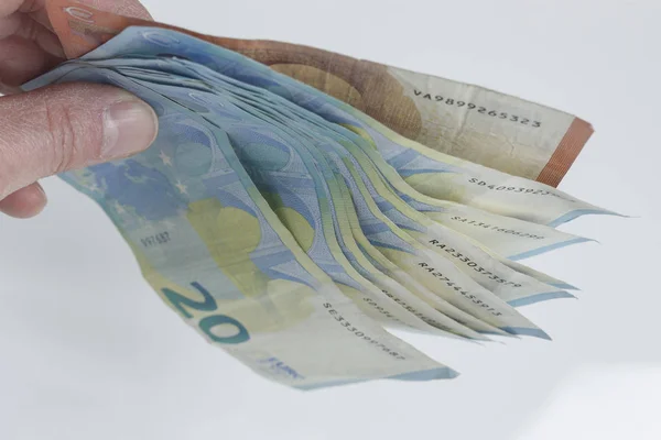 Banknotes between the fingers of a hand on a white background