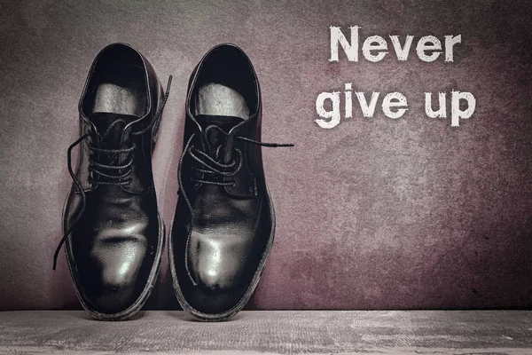 Nunca desista de prancha marrom e sapatos de trabalho no chão de madeira — Fotografia de Stock