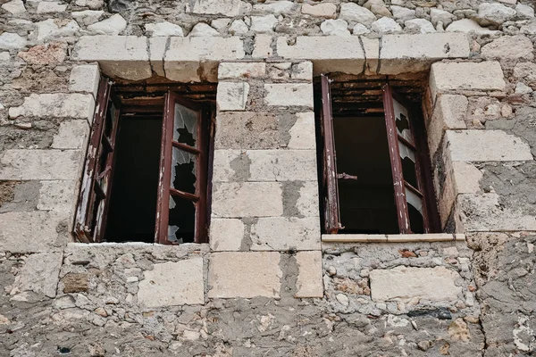 Broken windows with bars of an abandoned house
