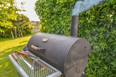 Sıcak kömürle hazırlanmış ve lezzetli dumanlı domuz pastırması pişiren küçük bir barbekü.