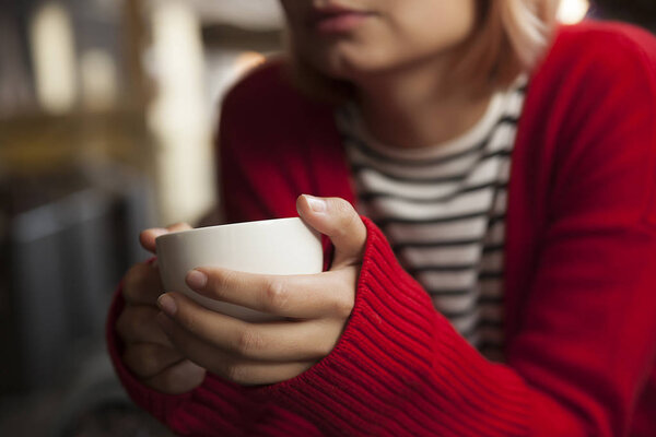 молодая красивая девушка пьет чай из белой кружки, молодая блондинка пьет кофе в кафе, открытое кафе
