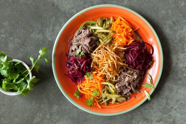 Parlak tabakta sığır etli sebze salatası, koyu ahşap masada gurme öğle yemeği, parlak Asya yemeği.