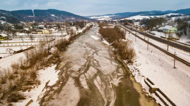 Donmuş kış nehri. Karlı köy, yol ve demiryolu havadan görülebiliyor. Baharın başlarında eriyen kar ve buz.
