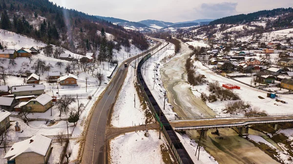 Winter travel. Train and bus moving in winter valley. Aerial view of river Dniester in Carpathian mountains.