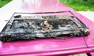 Bilgisayar ateşi. Kırık dizüstü bilgisayar sıcak ateşin ateşiyle mahvoldu. Yok edilmiş defter, erimiş plastik. Bilgisayar hasarı, veri imha kavramları.