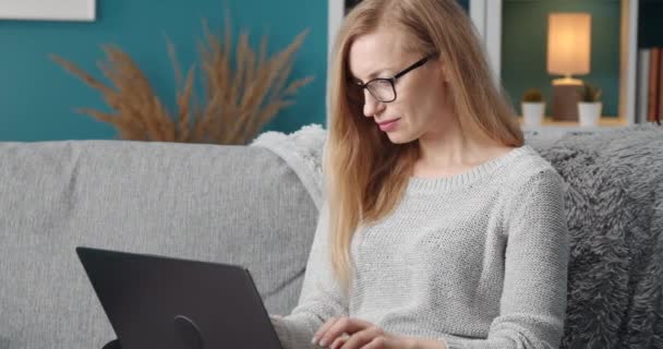 Geconcentreerde vrouw in bril met behulp van laptop voor werk op afstand — Stockvideo