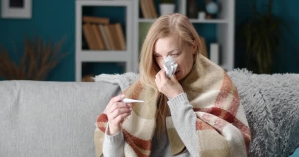 Chora kobieta kichająca w tkance i mierząca temperaturę — Wideo stockowe