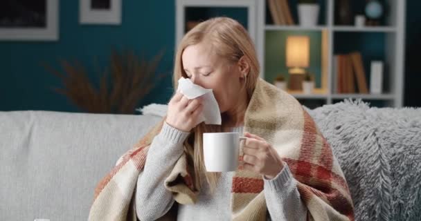 Zieke persoon die thee drinkt en niest terwijl hij op de bank zit — Stockvideo