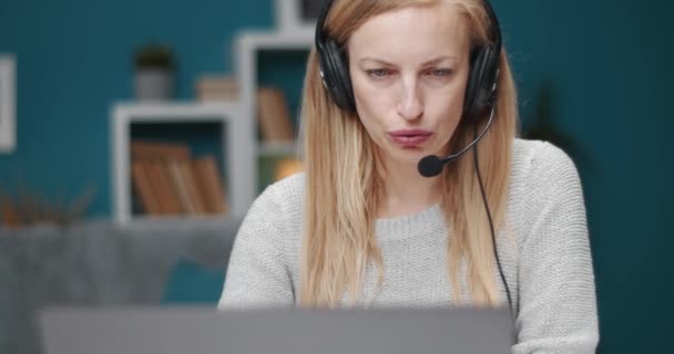 Primo piano di donna matura in cuffia utilizzando il computer portatile a casa — Video Stock