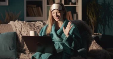 Bornozlu neşeli kadın evde video görüşmesi yapıyor.