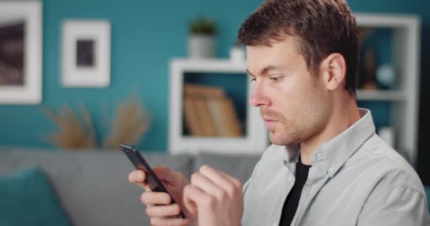 Vista lateral de homem bonito usando smartphone em casa — Vídeo de Stock