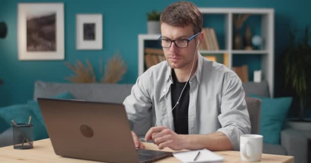 Man in earphones using laptop for online studying — Stock video