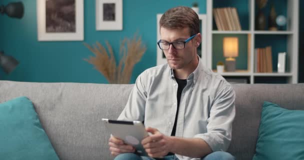 Homem barbudo relaxando no sofá e usando tablet digital — Vídeo de Stock