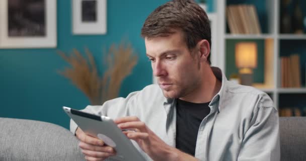 Primer plano del hombre guapo usando tableta digital en casa — Vídeo de stock