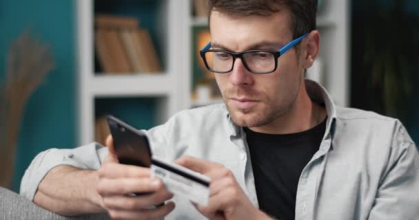 Jeune homme utilisant téléphone et carte de crédit pour les achats en ligne — Video