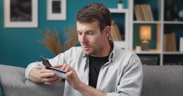 Man doing online payments on phone while sitting on couch — Αρχείο Βίντεο