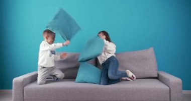 Group of two happy children fighting with pillows on couch