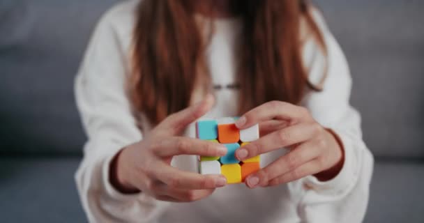 Primer plano de la chica que usa Rubiks Cube mientras está sentado en el sofá — Vídeo de stock