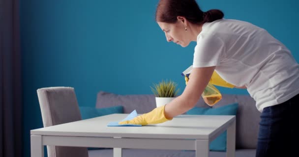 Side view of housewife in protective gloves cleaning table — Stok Video