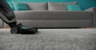 Evde halı yıkamak için süpürge kullanan bir kadın.