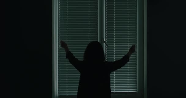 Rückansicht einer Frau, die zu Hause Jalousie am Fenster öffnet — Stockvideo