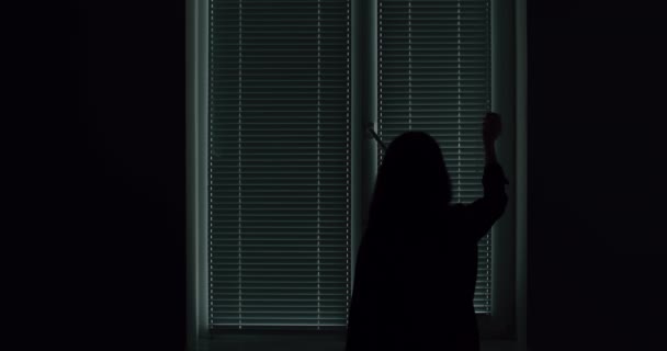 Volwassen vrouw in silhouet opening jaloezie op slaapkamer — Stockvideo
