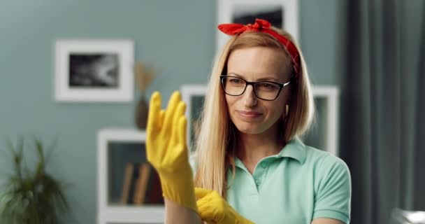 Vrouw met gele handschoenen tijdens het schoonmaken thuis — Stockvideo