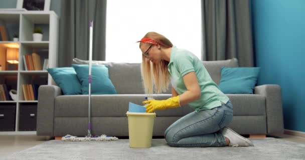 Side view of woman sitting near bucket with cleaning tools — Stock Video