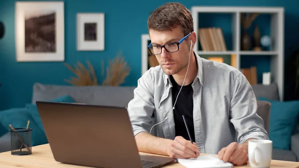 Dizüstü bilgisayara bakan adam not alıyor