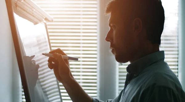 Businessman writing on whiteboard, side — Stock Photo, Image