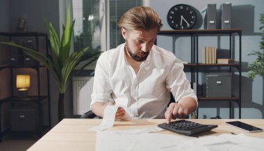 İş adamı hesap makinesinde numaraları kontrol ediyor