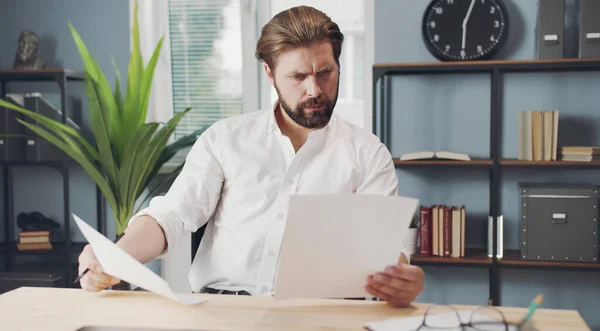 Elinde kağıtlar olan konsantre bir iş adamı.