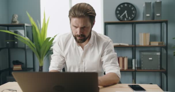 Knappe zakenman werkt aan laptop op kantoor — Stockvideo