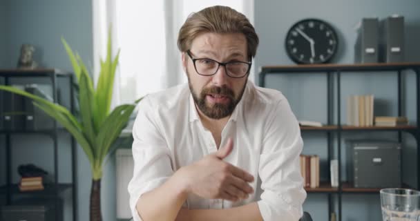Бородатый бизнесмен ведет видеоразговор в офисе — стоковое видео