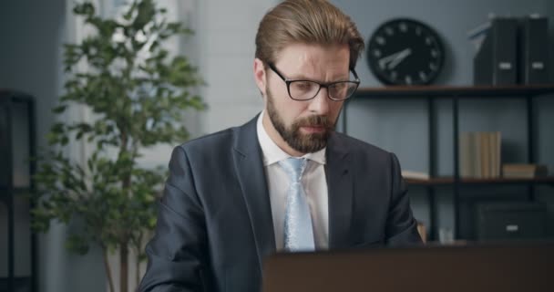 Зрілий бізнесмен в окулярах використовує ноутбук для роботи — стокове відео