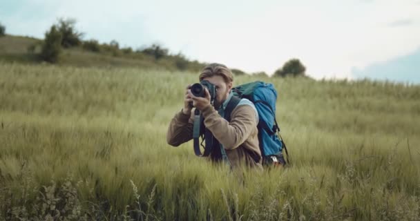 Vousatý muž stojící na zeleném poli a fotí — Stock video