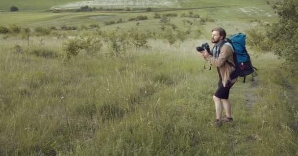 Fotograf står på kullen och gör bilder av naturen — Stockvideo