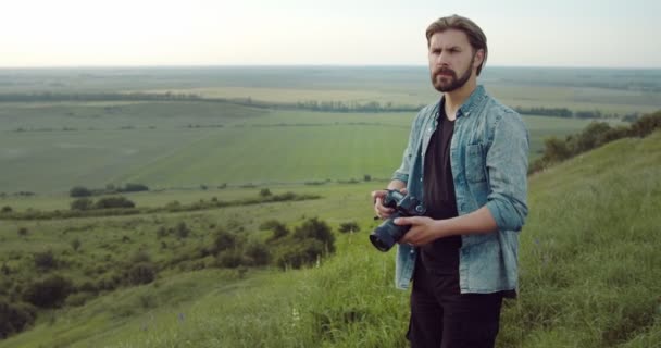 Baard man staat op de heuvel en met behulp van digitale camera — Stockvideo